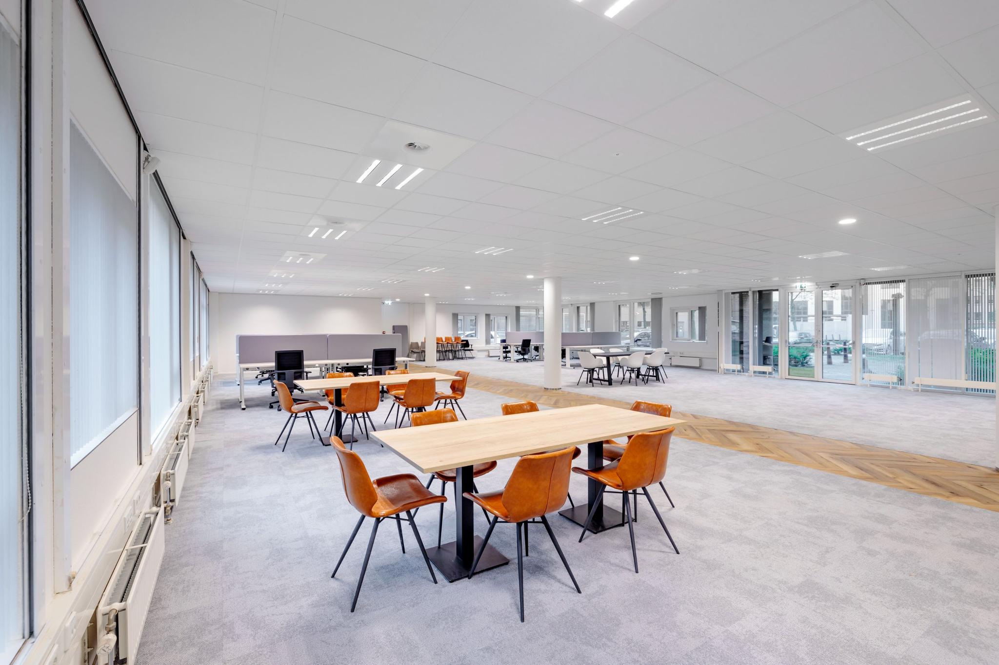 Moderne, open kantoorruimte aan de Hullenbergweg met flexwerkplekken en vergadertafels.