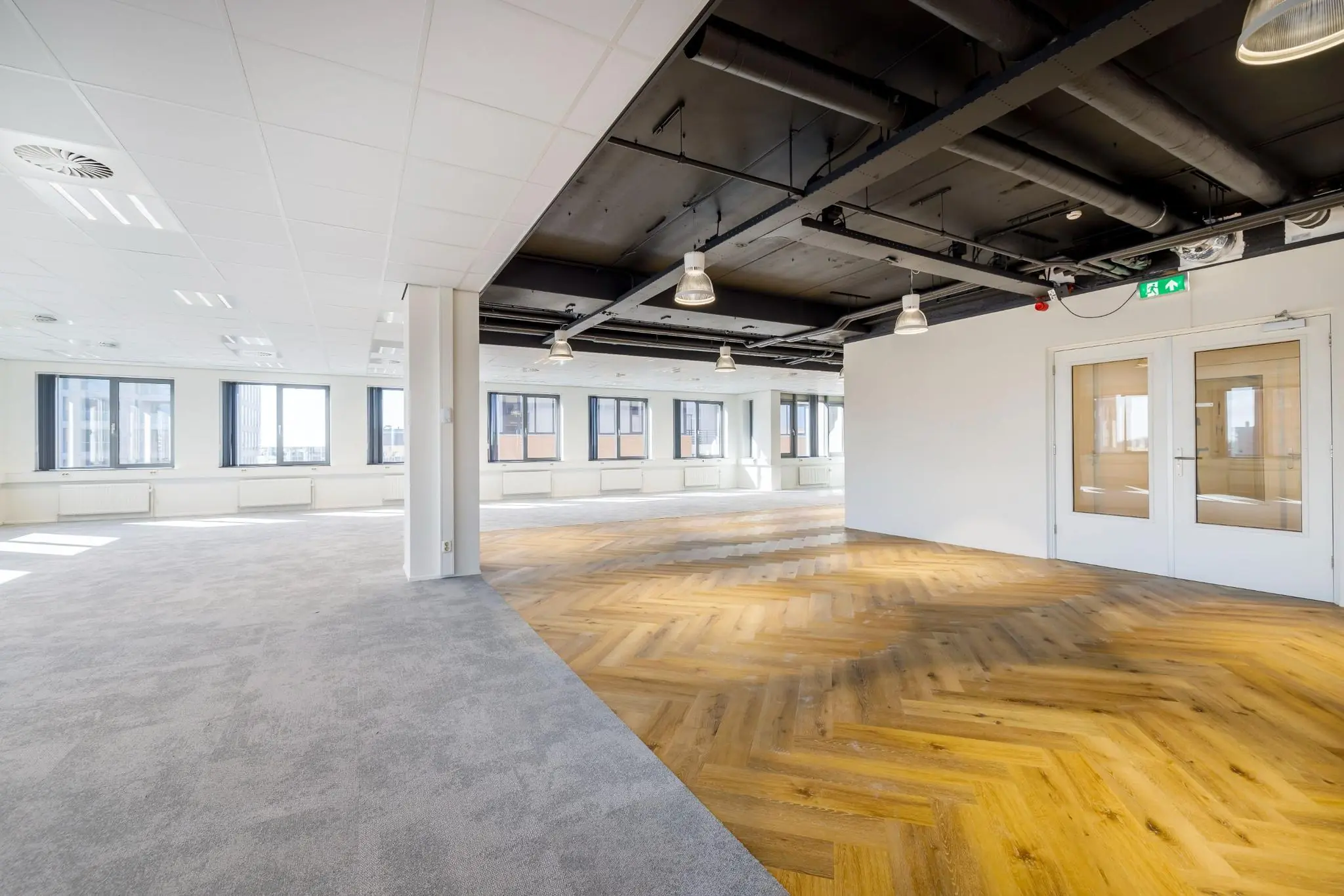 Licht en modern kantoorpand aan de Karspeldreef met een combinatie van tapijt en visgraat houten vloer.