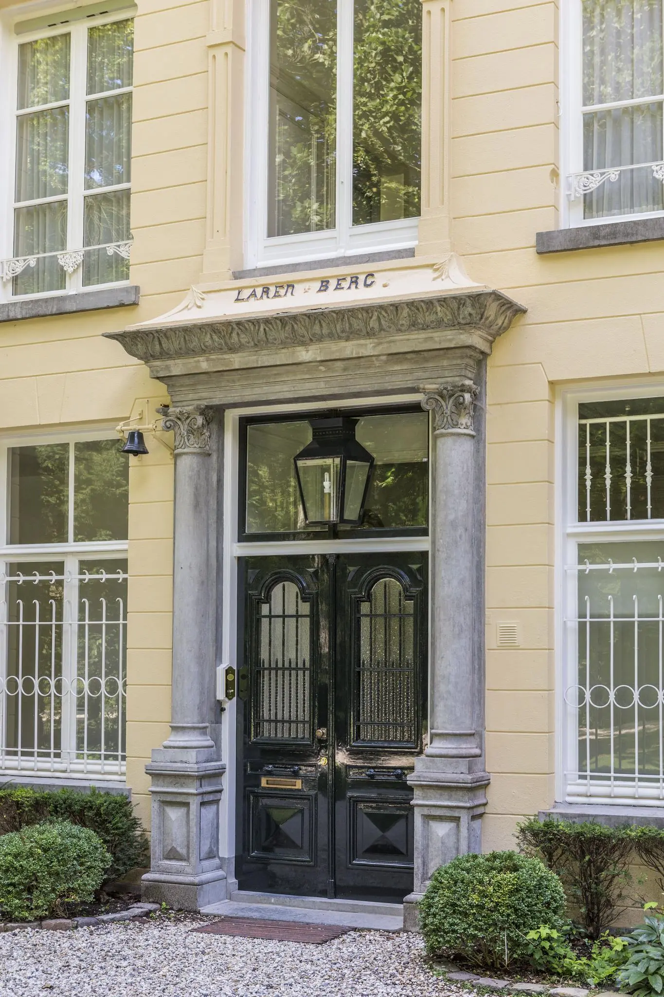 Voordeur van herenhuis 'Larenberg' aan de Naarderstraat met klassieke omlijsting en sierlijke details.