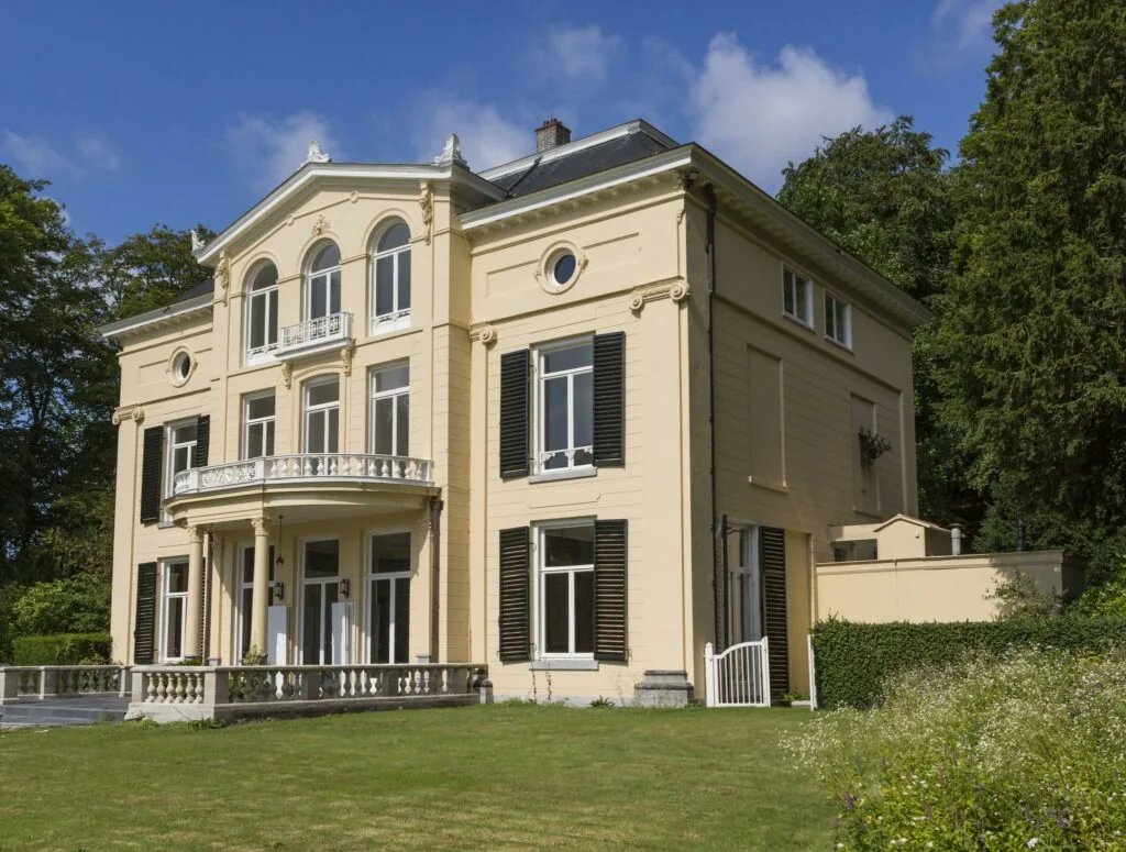 Klassiek herenhuis aan de Naarderstraat met beige gevel, zwarte luiken en een sierlijk balkon.