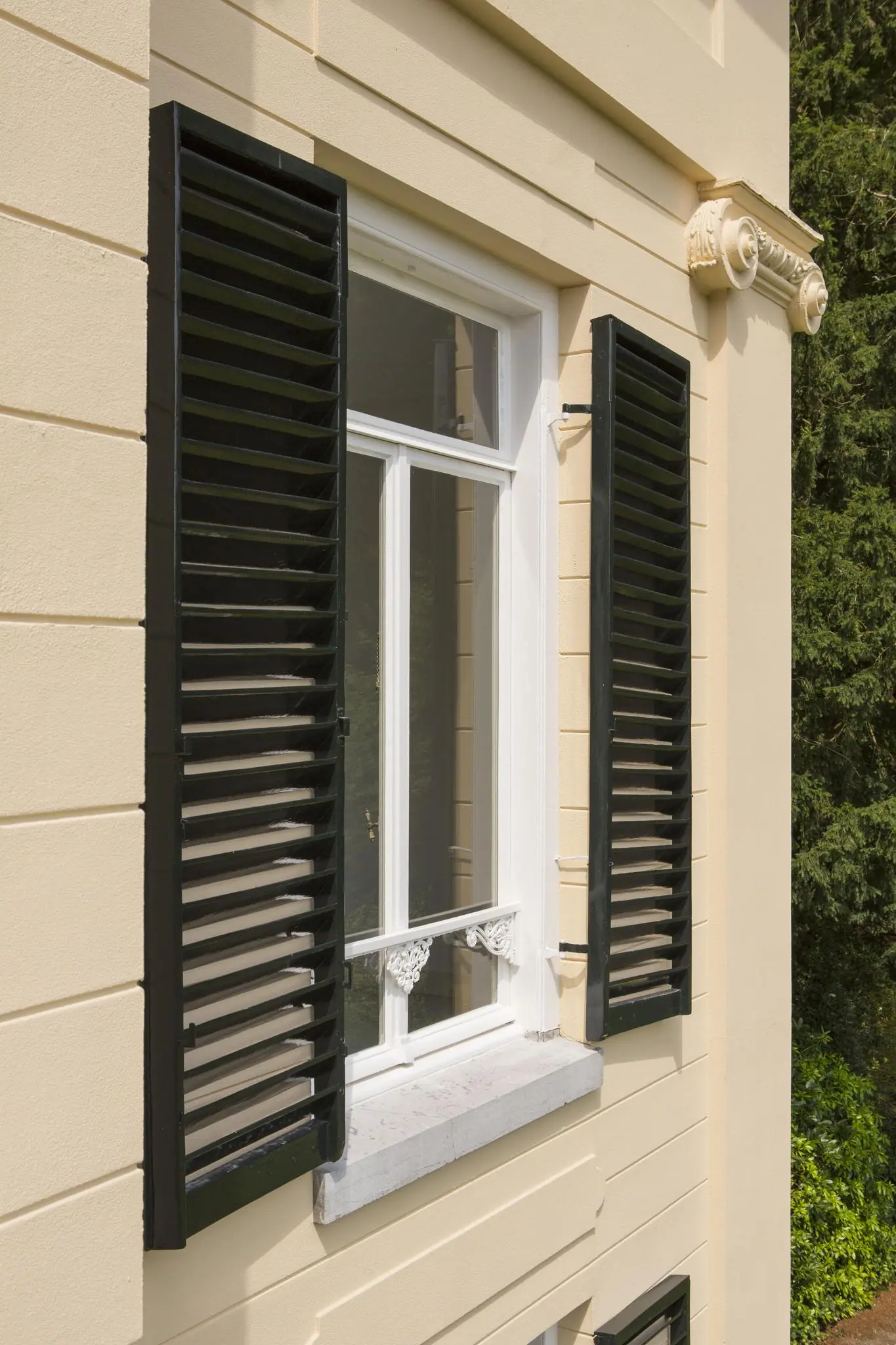 Detail van een klassiek raam met zwarte luiken en witte omlijsting aan de gevel van een pand aan de Naarderstraat.