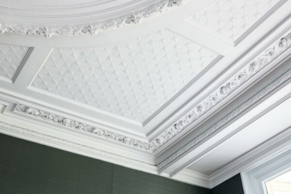 Plafond met sierlijke witte stucornamenten en reliëfpatronen in een pand aan de Naarderstraat.