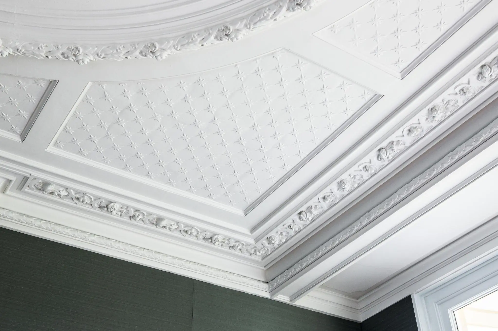 Plafond met sierlijke witte stucornamenten en reliëfpatronen in een pand aan de Naarderstraat.
