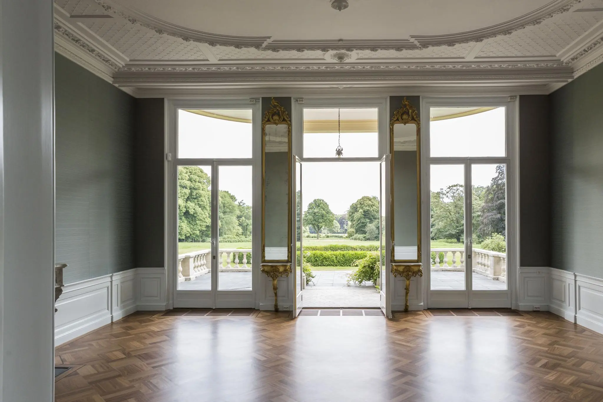 Luxe interieur met openslaande deuren naar een statig terras en uitzicht op een groen landgoed aan de Naarderstraat.