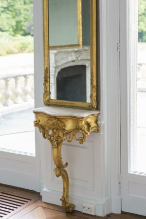Goudkleurige wandconsole met marmeren blad en spiegel in een klassieke interieurstijl aan de Naarderstraat.