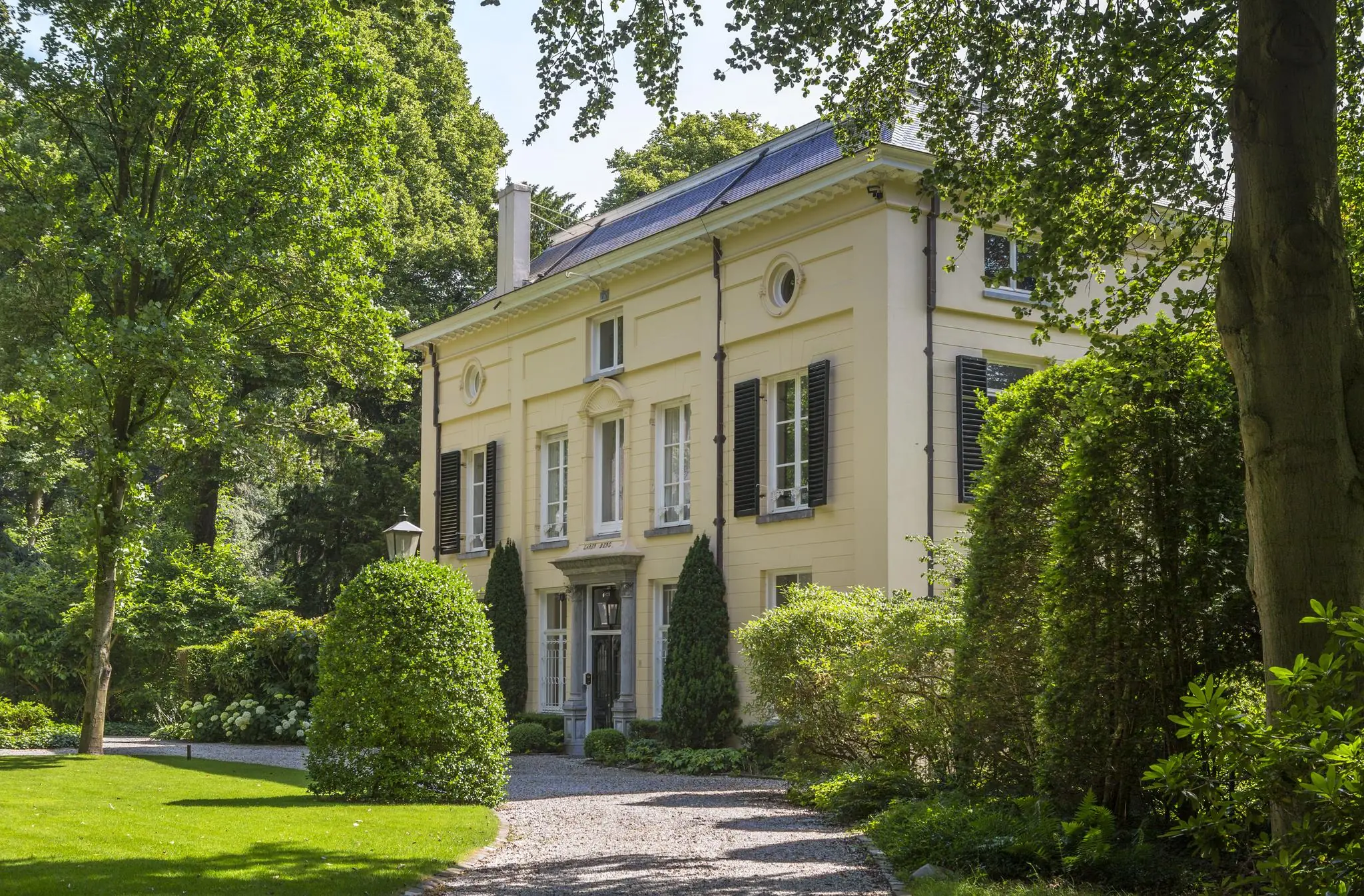 Klassiek herenhuis aan de Naarderstraat omgeven door een groene, verzorgde tuin.