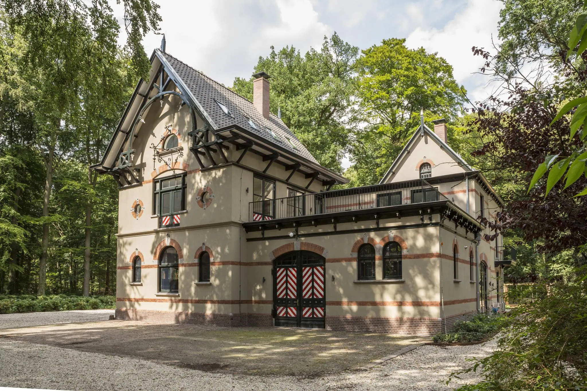 Historisch pand aan de Naarderstraat omgeven door groen en voorzien van sierlijke geveldetails en luiken.