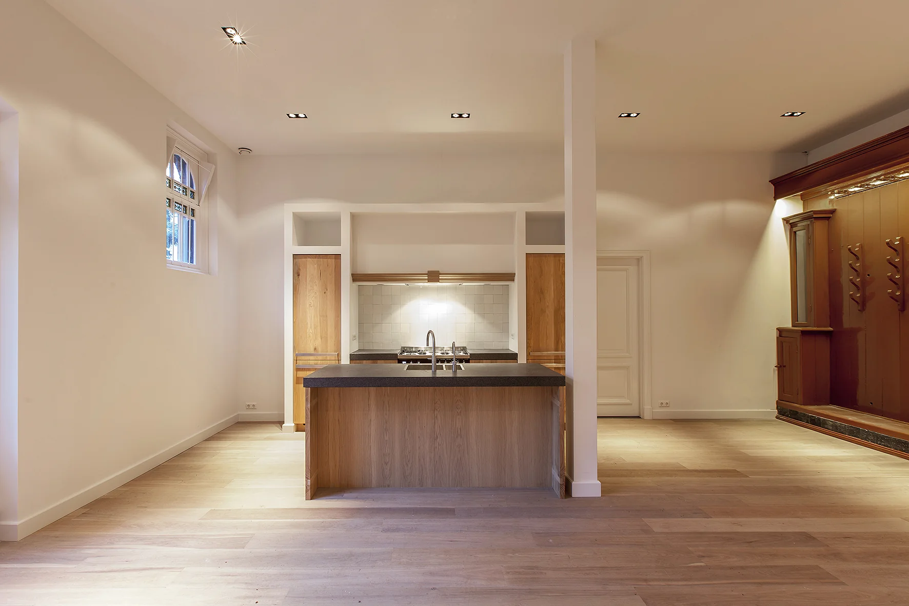 Moderne open keuken met kookeiland en houten accenten aan de Naarderstraat.