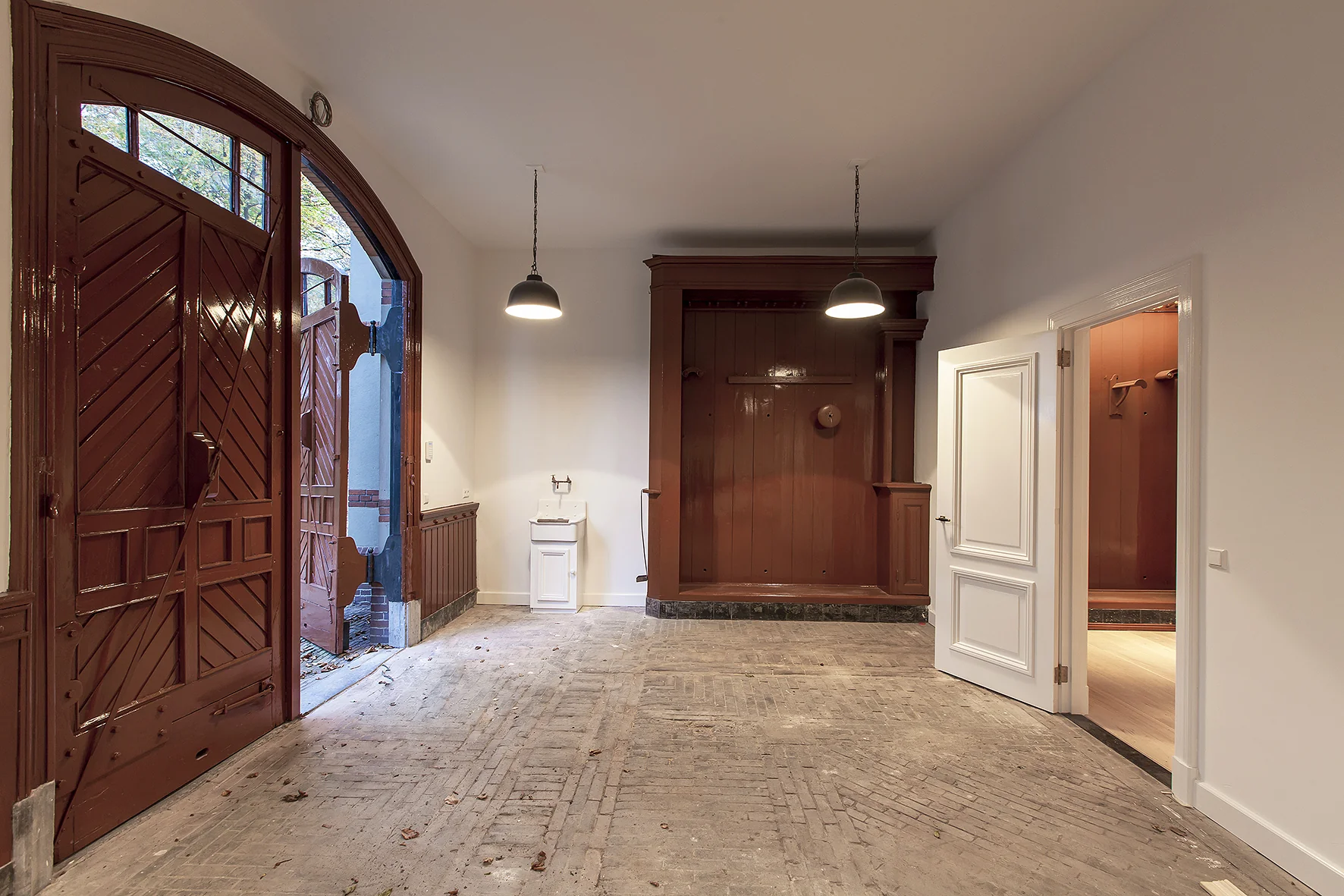 Binnenruimte met open houten garagedeuren, een wastafel en een doorgang naar een aangrenzende kamer aan de Naarderstraat.