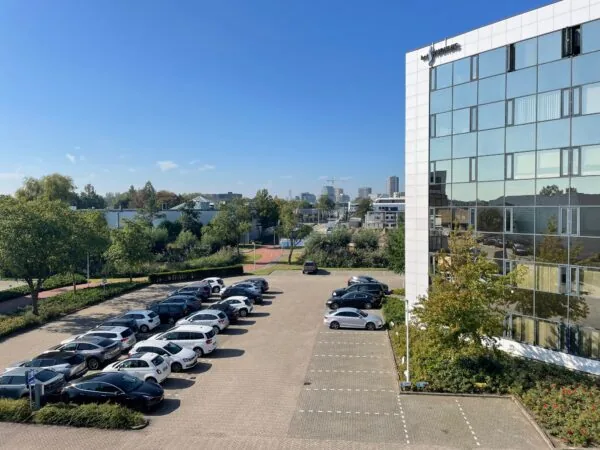 Kantoorgebouw aan de Cypresbaan met aangrenzende parkeergarage op een zonnige dag.