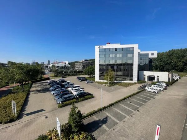 Kantoorgebouw aan de Cypresbaan met parkeerterrein en omliggend groen op een zonnige dag.