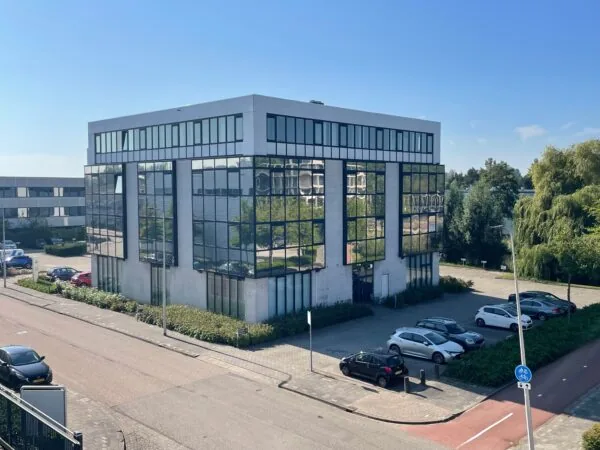Modern kantoorgebouw aan de Cypresbaan met spiegelende ramen en omliggende parkeerplaatsen.