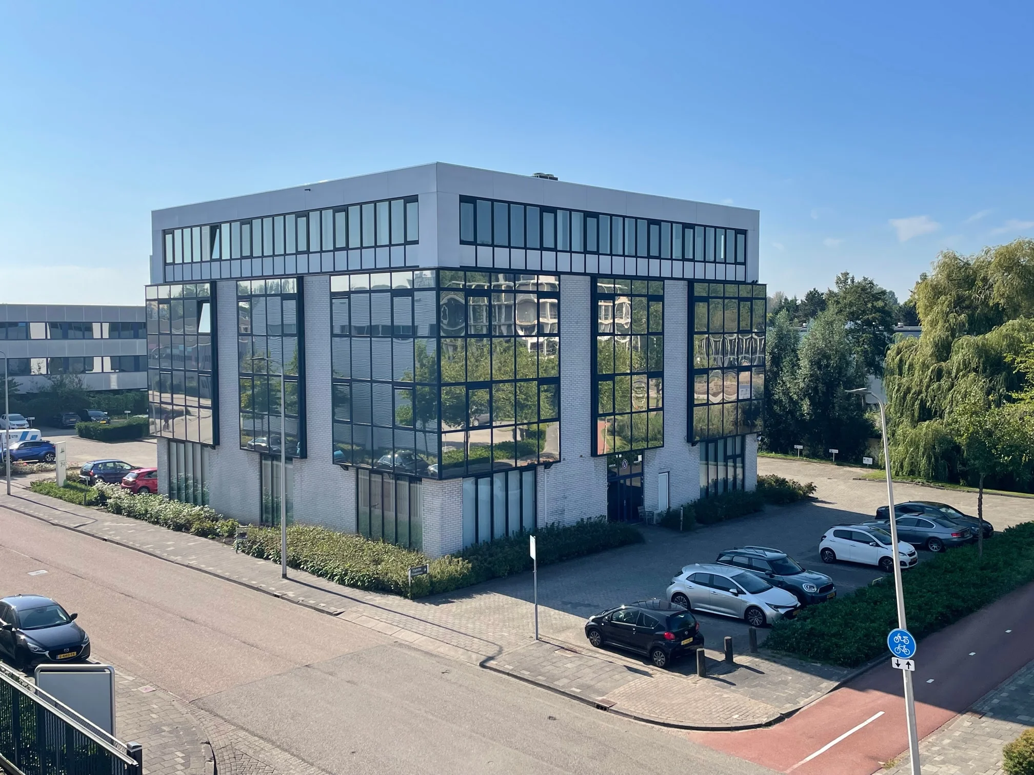Modern kantoorgebouw aan de Cypresbaan met spiegelende ramen en omliggende parkeerplaatsen.