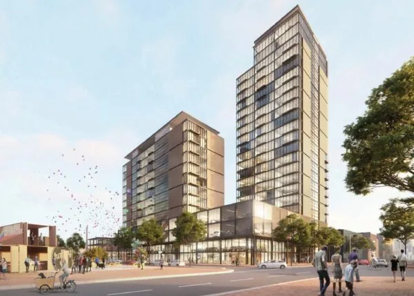 Moderne hoogbouw aan de Melkwegstraat met glazen gevels, omringd door voetgangers, bomen en kleurrijke ballonnen in de lucht.