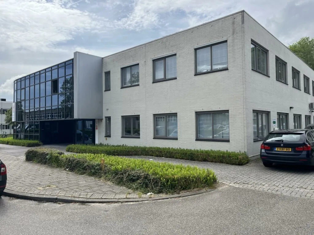 Wit kantoorgebouw aan de Computerweg met grote spiegelramen en geparkeerde auto's op de oprit.