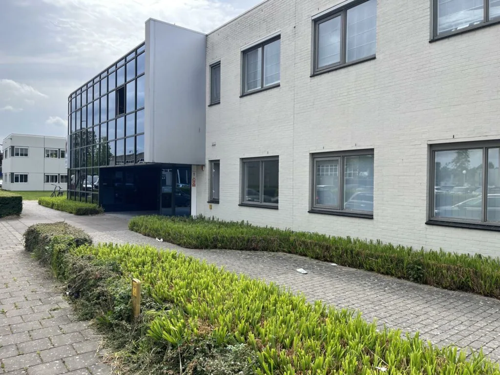 Wit kantoorgebouw aan de Computerweg met grote ramen en omliggende groenstroken.