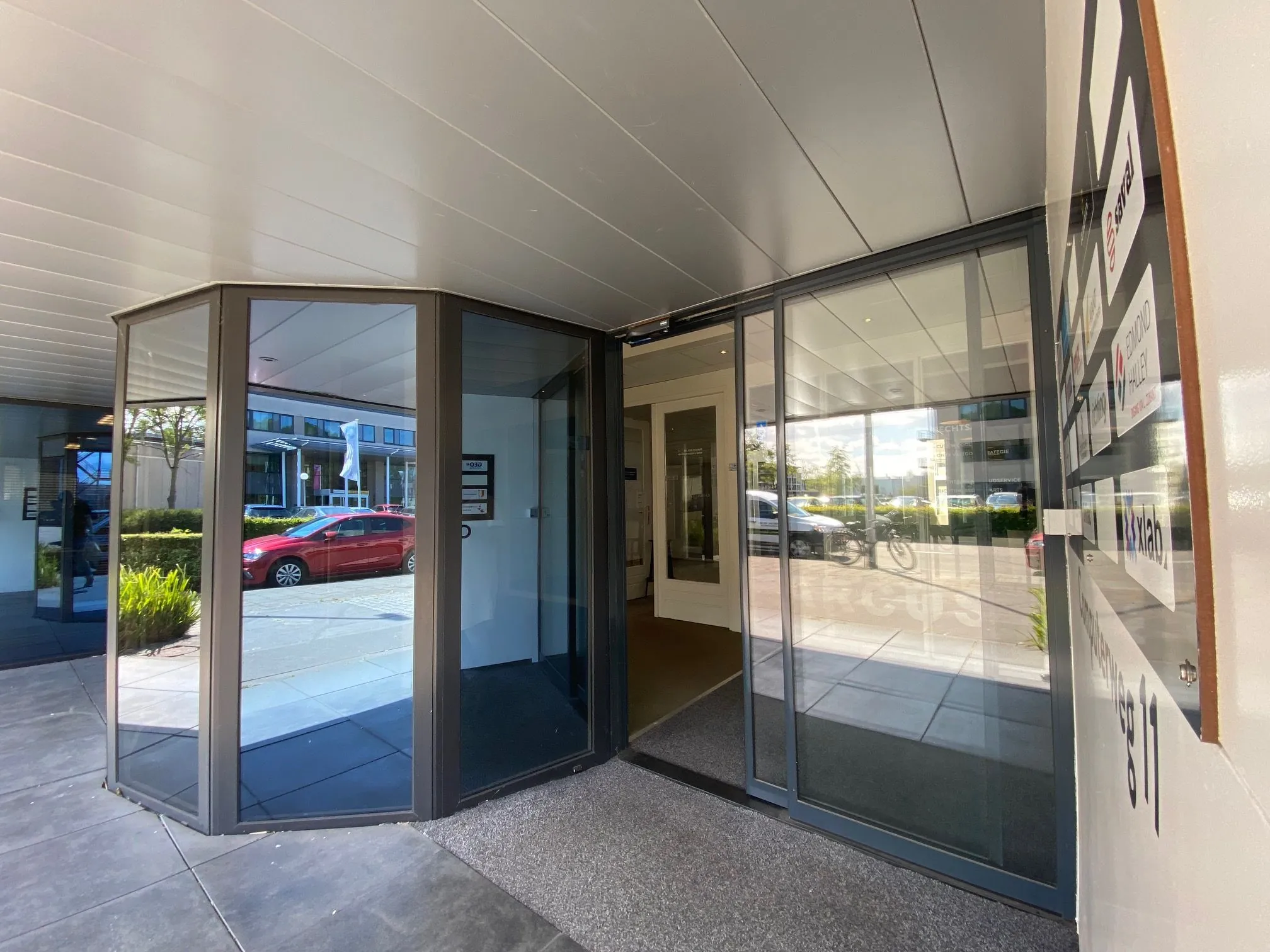 Ingang van een kantoorpand aan de Computerweg met glazen draaideur en bedrijvenbord.
