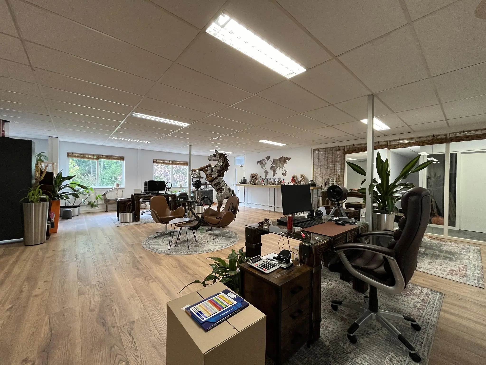 Modern kantoorinterieur aan de Computerweg met houten vloer, bureaus, planten en kunstobjecten.