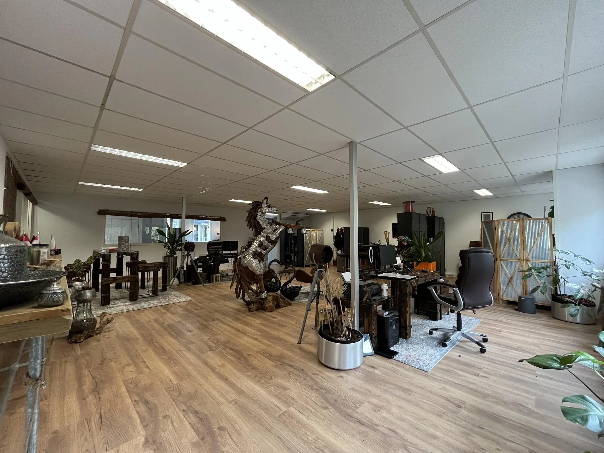 Modern ingerichte kantoorruimte aan de Computerweg met houten vloeren, bureaus, planten en een opvallend houten kunstpaard.