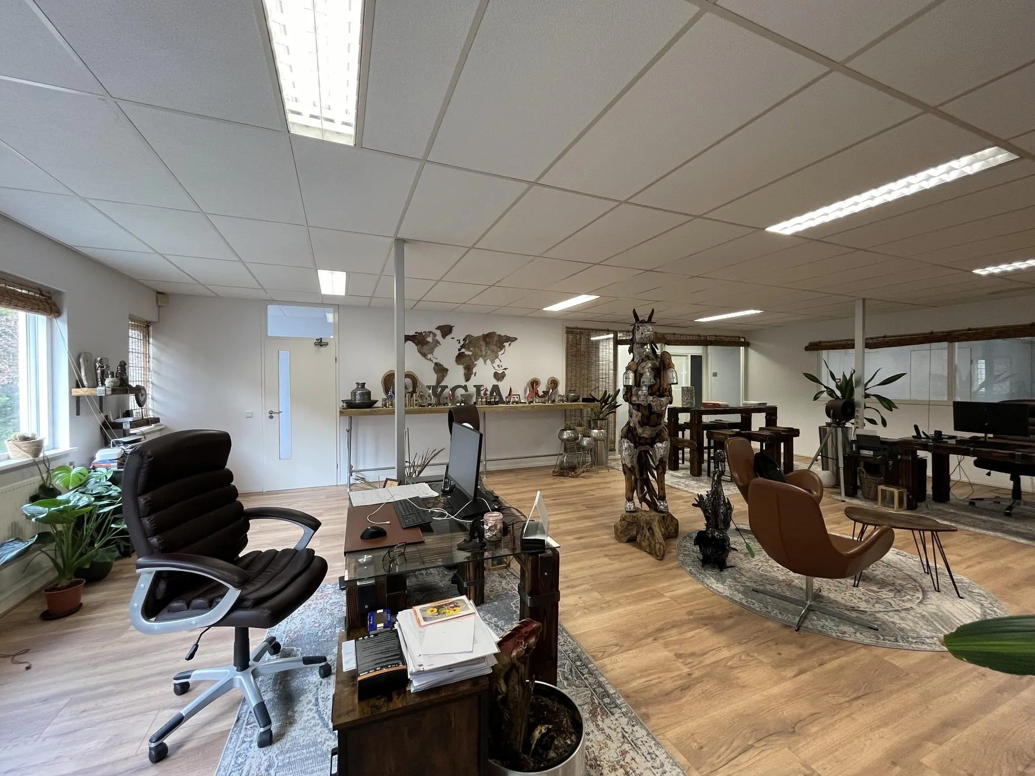 Moderne kantoorruimte aan de Computerweg met houten vloeren, designmeubels en een opvallend metalen standbeeld.