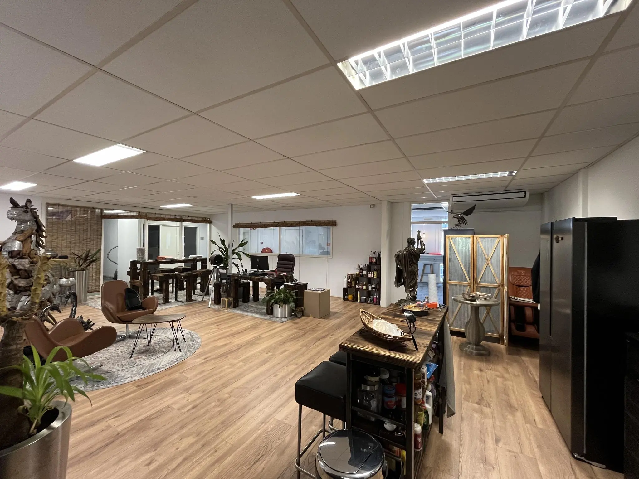 Modern kantoorinterieur aan de Computerweg met houten vloeren, zitgedeeltes, planten en diverse decoratieve elementen.