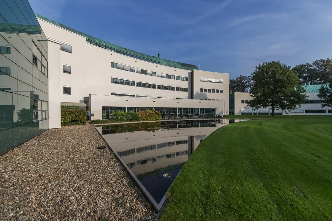 Modern kantoorgebouw Sparrenheuvel met spiegelvijver en verzorgd gazon op de voorgrond.