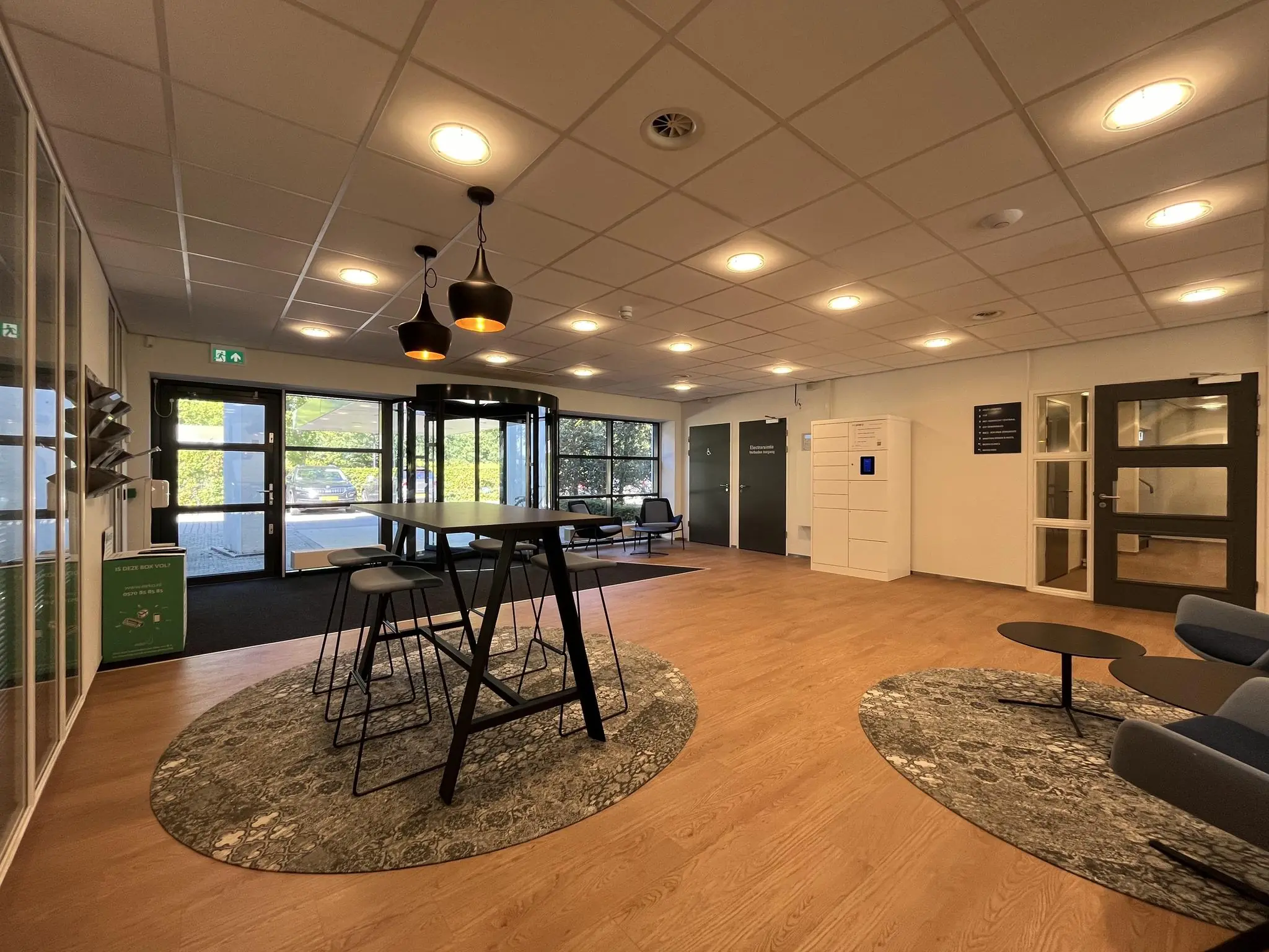 Moderne wachtruimte in gebouw Sparrenheuvel met zitgelegenheid, hoge tafel en pakketkluis.