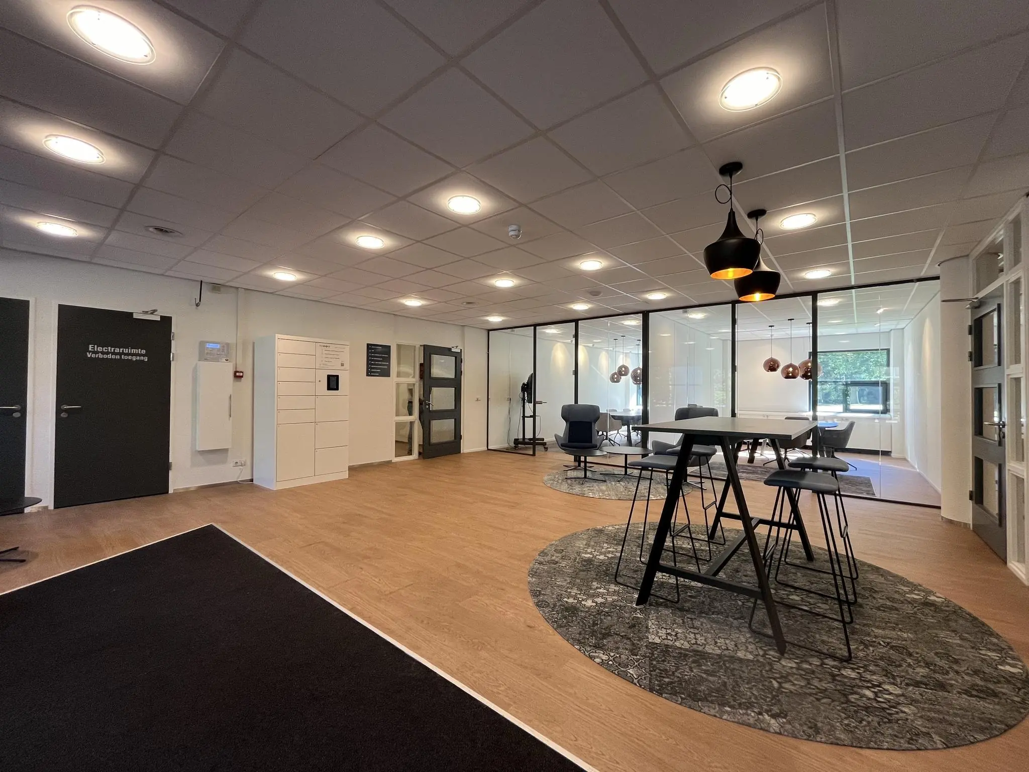 Moderne kantoorruimte in Sparrenheuvel met zitgedeelte, hoge tafel en glazen vergaderruimtes.