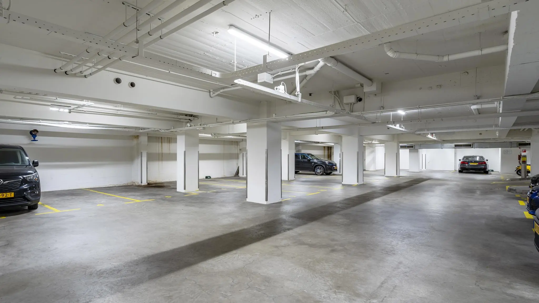 Ondergrondse parkeergarage aan de Coolsingel met enkele geparkeerde auto's en betonnen pilaren.