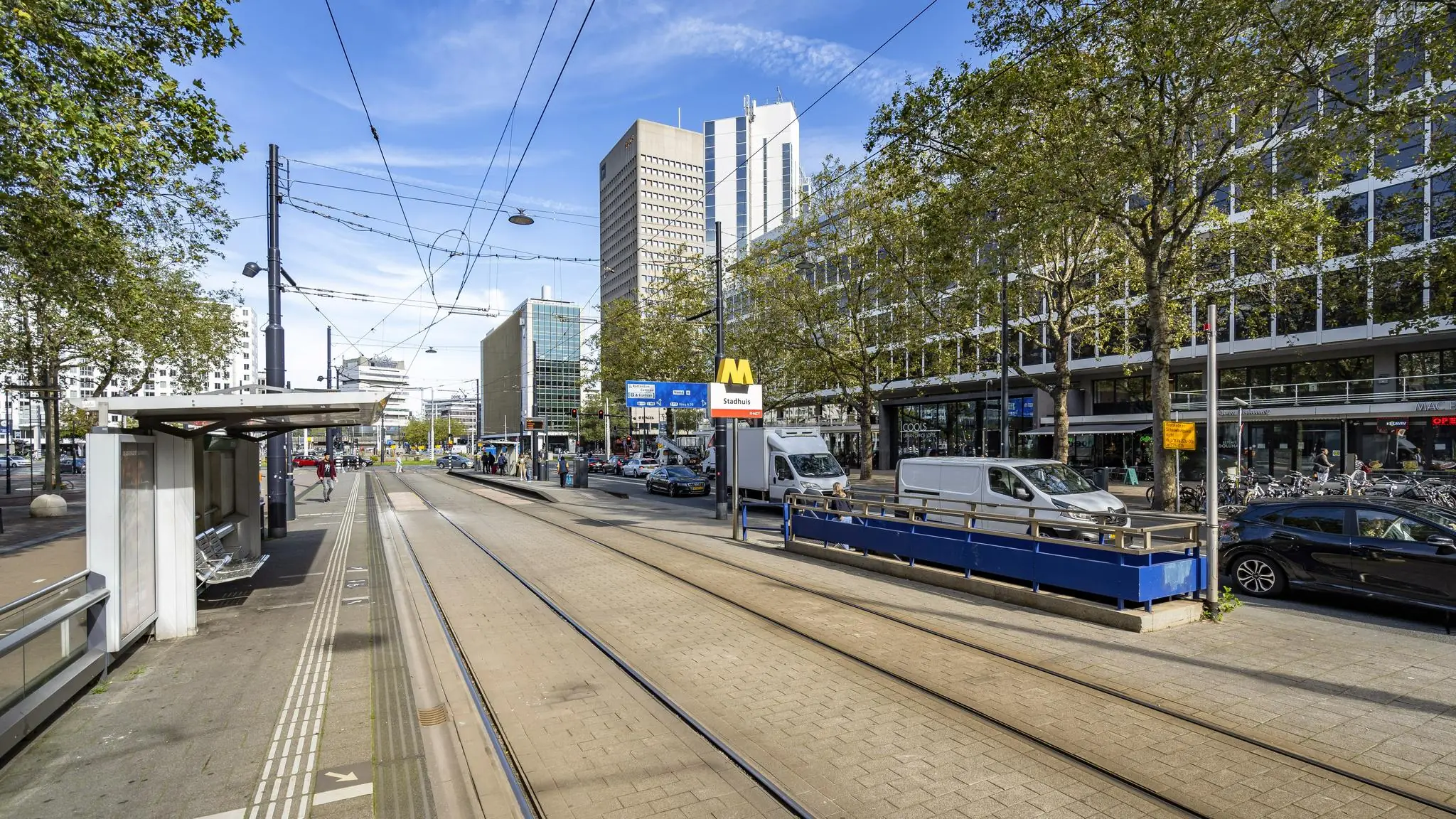 Tramhalte en metrostation Stadhuis aan de Coolsingel in Rotterdam met omliggende hoogbouw en winkelpanden.