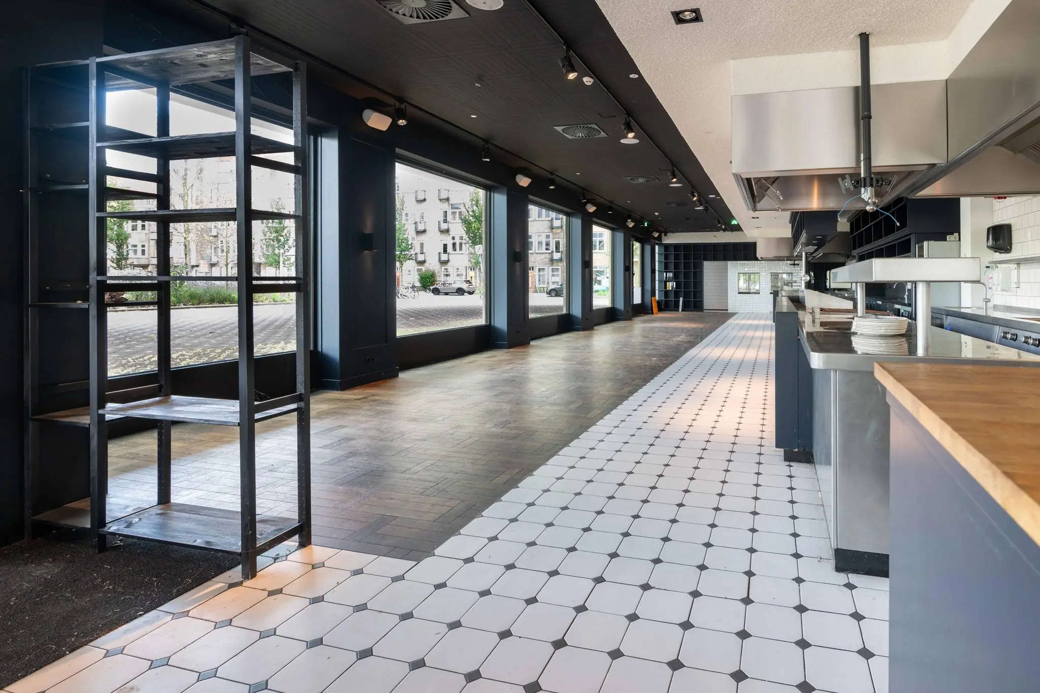 Leeg restaurantinterieur aan het Stadionplein met open keuken, grote ramen en betegelde vloer.