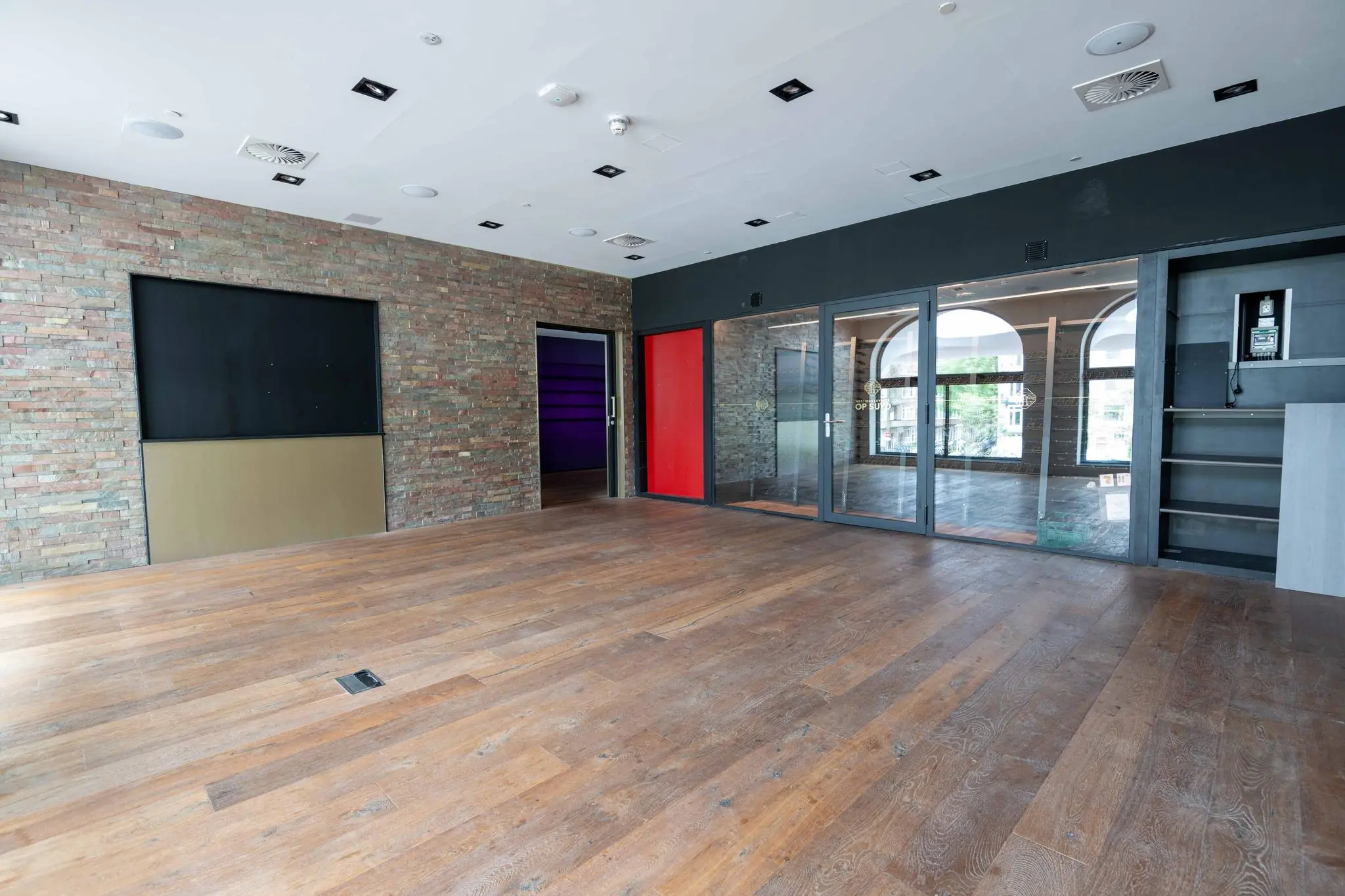 Leeg modern interieur met houten vloer, bakstenen muur en glazen deuren aan het Stadionplein.