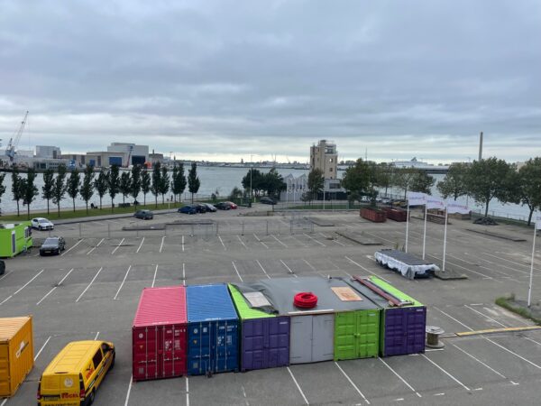 Leeg parkeerterrein aan de Sluisjesdijk met gekleurde containers, geparkeerde voertuigen en uitzicht op de haven.