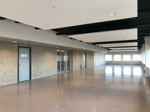 Lege, moderne kantoorruimte in het Hofplein-gebouw met grote ramen en een gladde vloer.