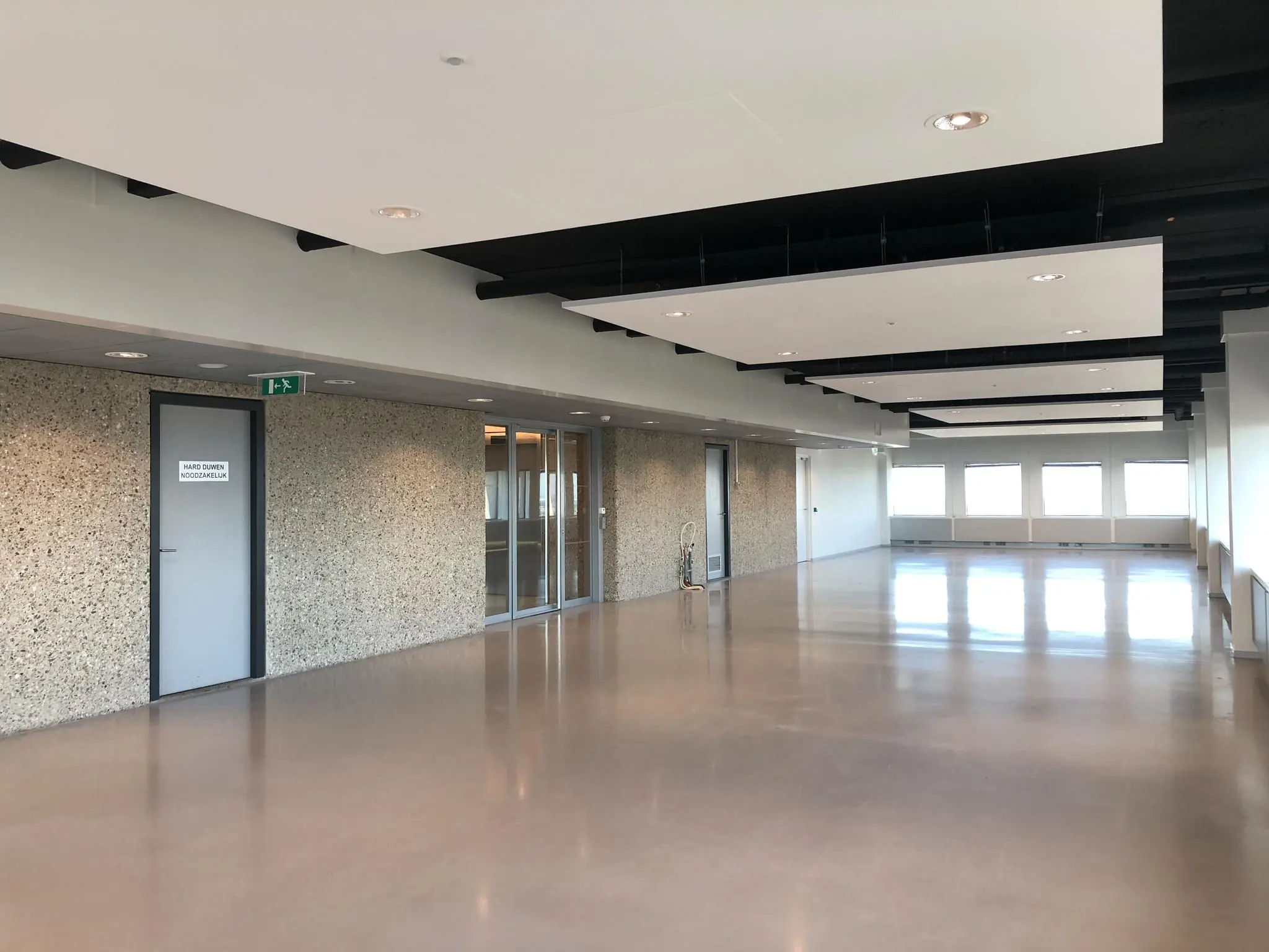 Lege, moderne kantoorruimte in het Hofplein-gebouw met grote ramen en een gladde vloer.