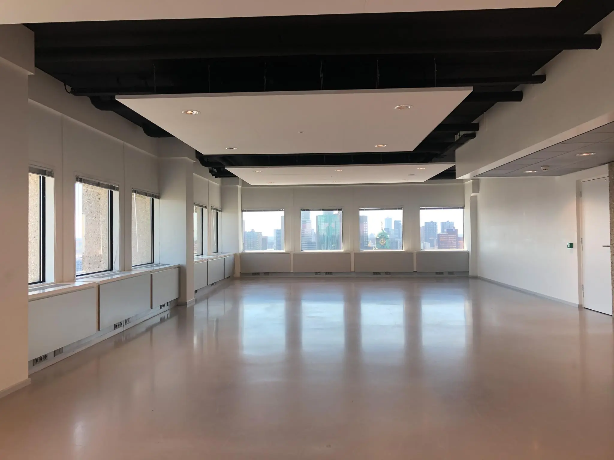 Leeg kantoorruimte met grote ramen en uitzicht op de Rotterdamse skyline vanaf Hofplein.