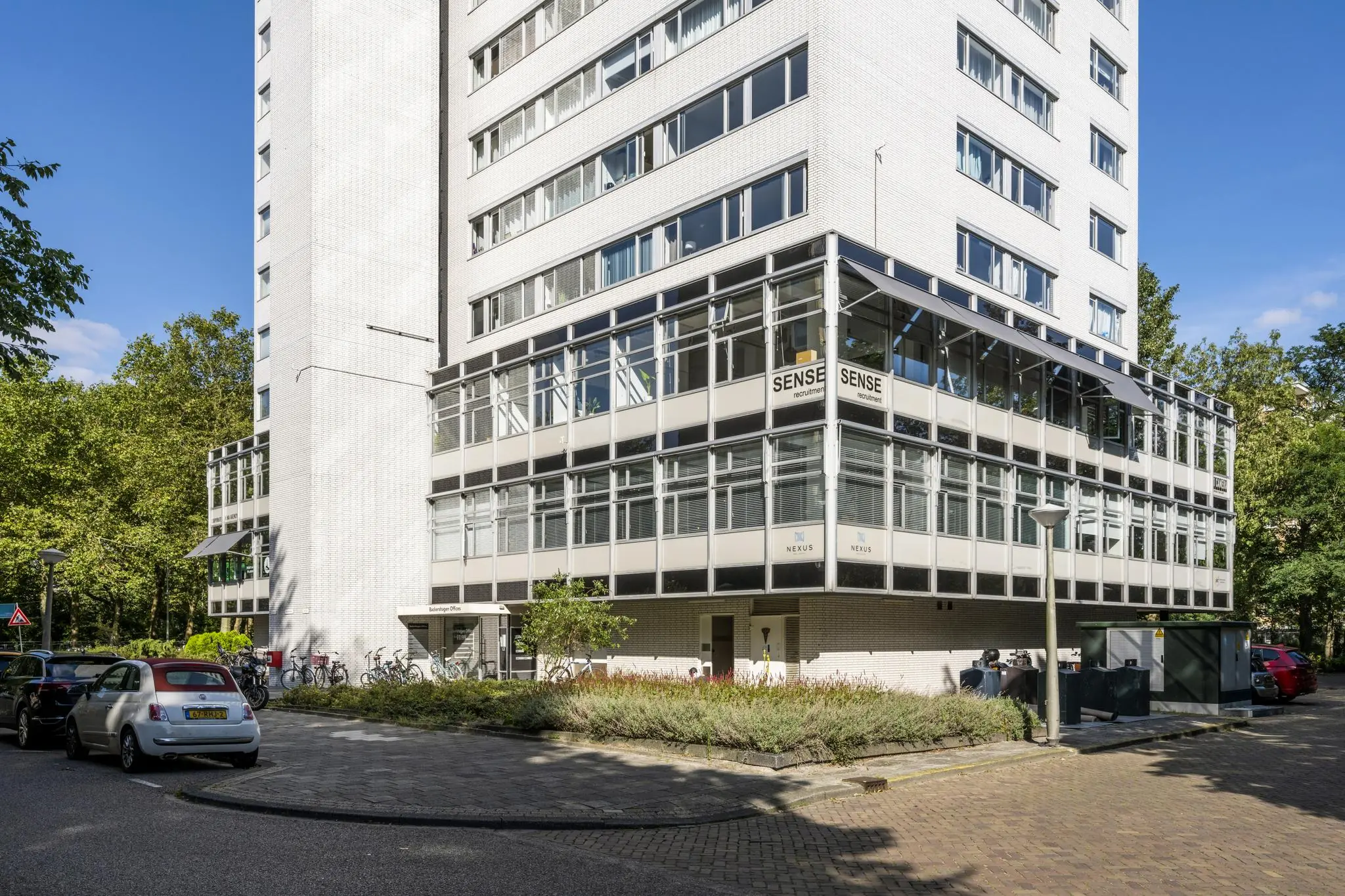 Wit appartementen- en kantoorgebouw aan de Backershagen met glasgevels en bordjes van Sense en Nexus.