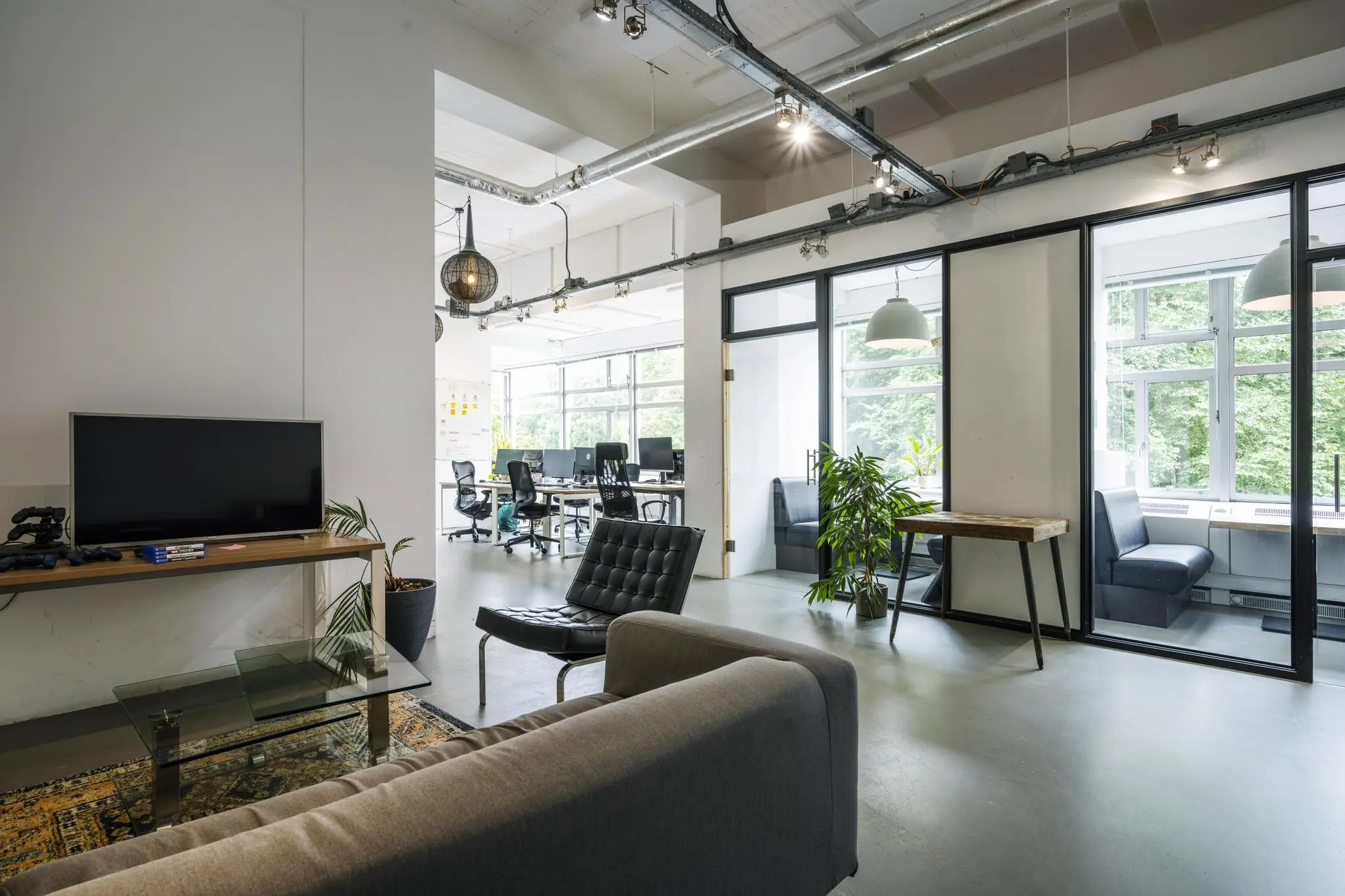 Modern en licht kantoorinterieur met open werkplekken, vergaderruimtes en een loungehoek.