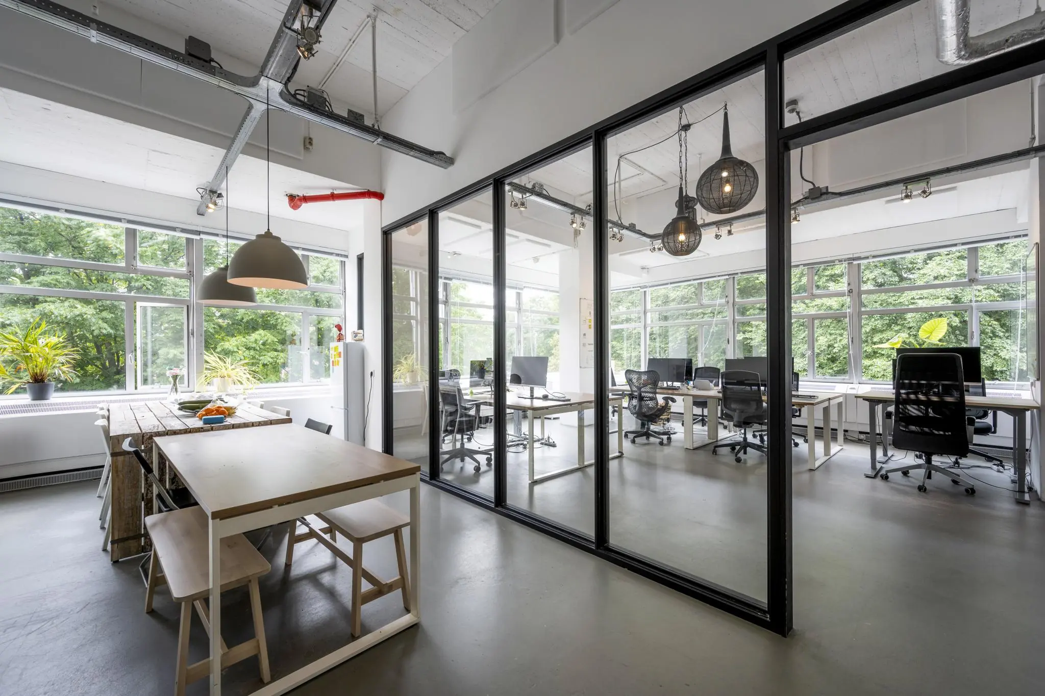 Moderne en lichte kantoorruimte met glazen wanden, een open werkplek en een gemeenschappelijke tafel bij de ramen.