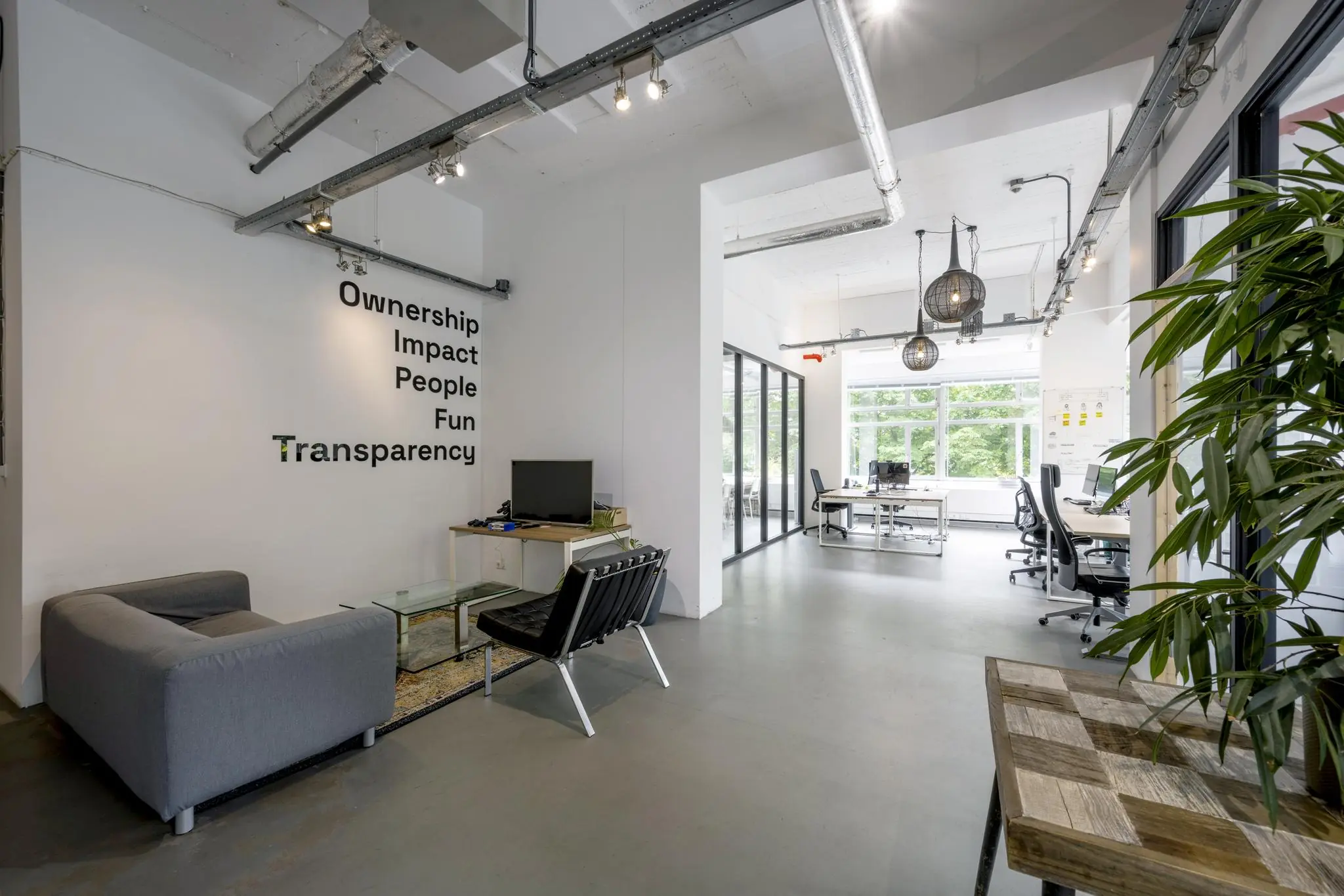 Modern kantoorinterieur van Backershagen met open werkplekken, zithoek en kernwaarden op de muur.