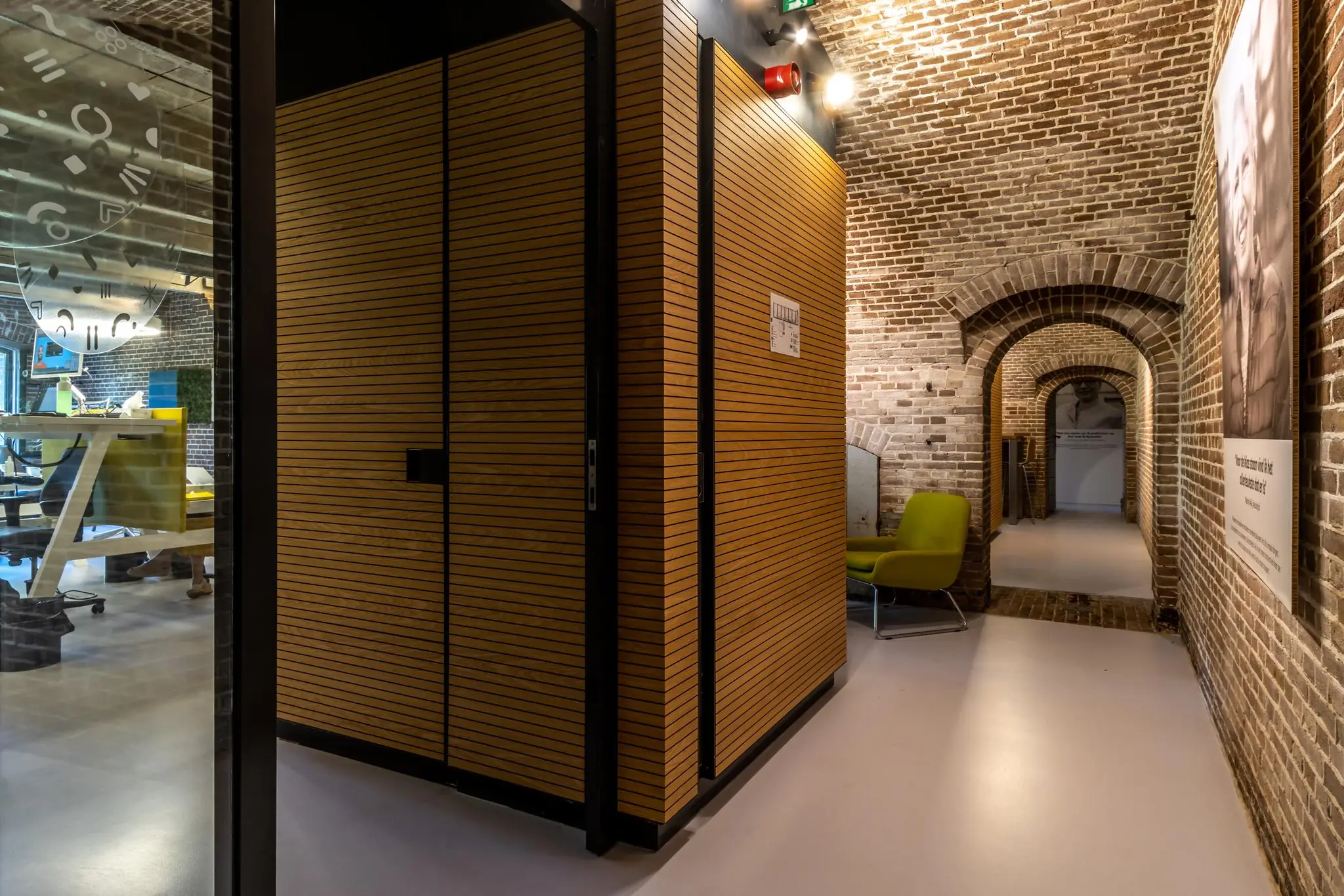 Modern interieur met houten wanden en glazen vergaderruimte binnen een historische bakstenen fortgang aan de Fortweg.
