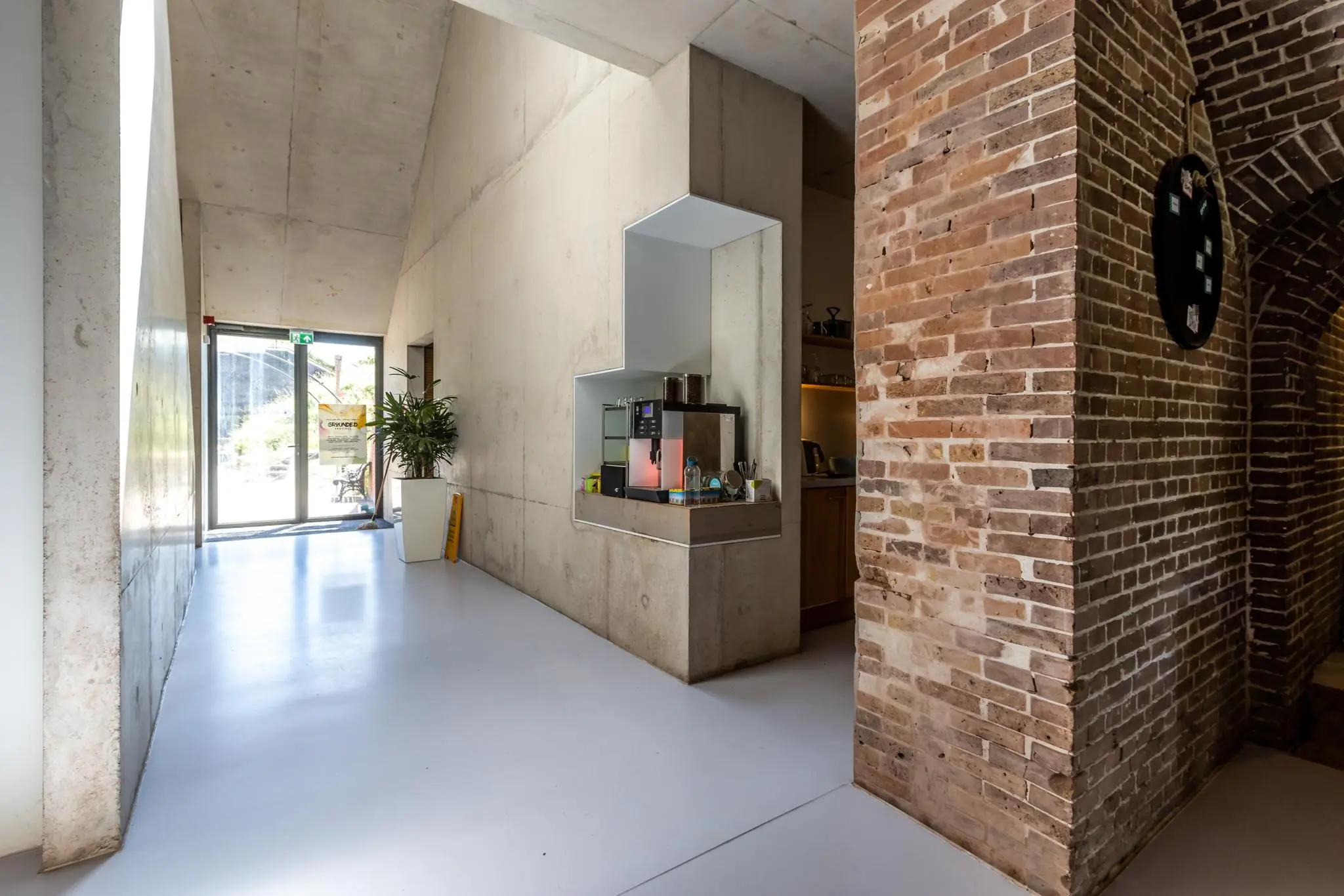 Hal met betonnen en bakstenen muren, een ingebouwde koffiemachine en een glazen deur naar buiten bij Fortweg.