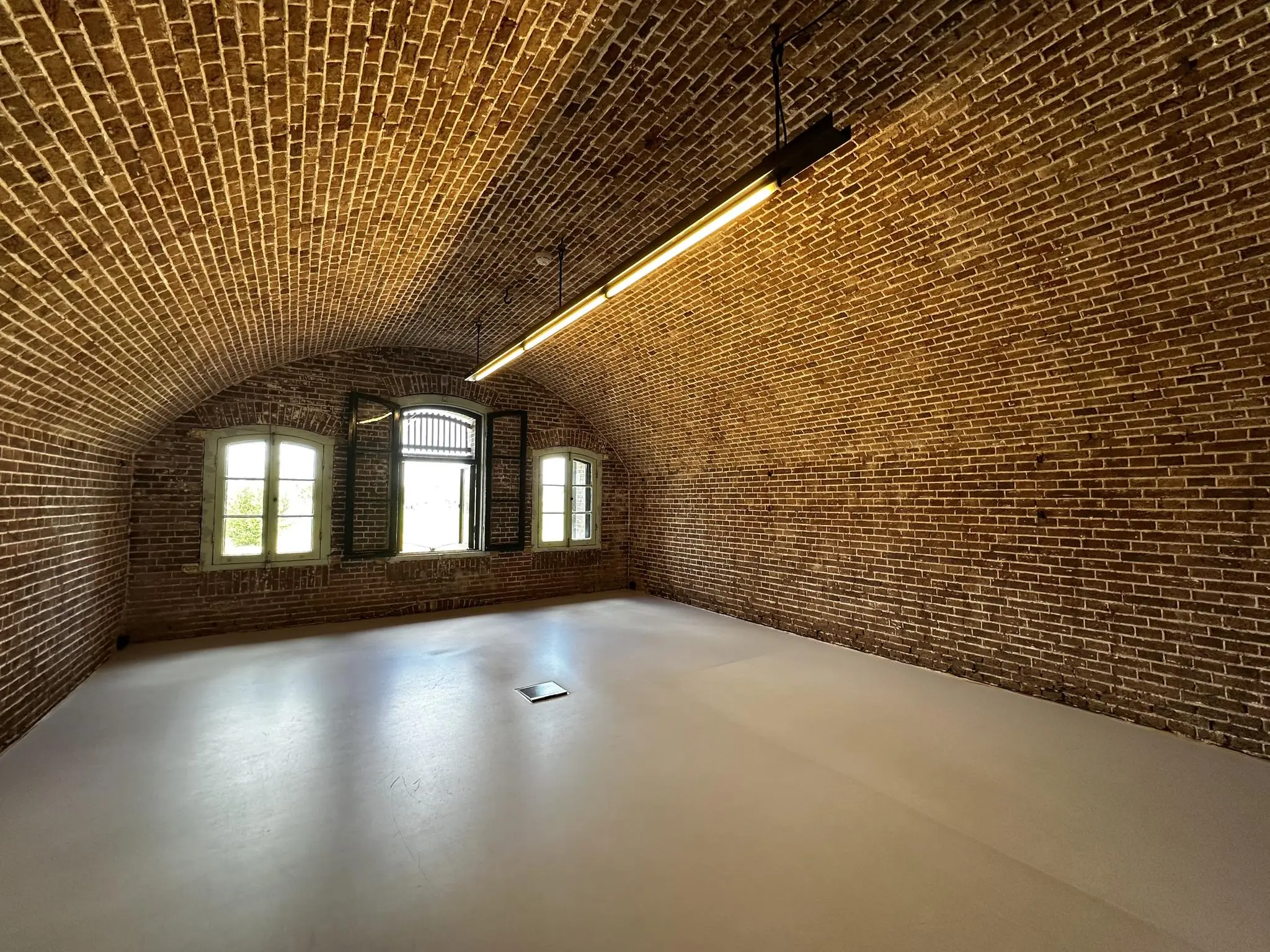 Bakstenen gewelfruimte met ramen en moderne verlichting in Fortweg.
