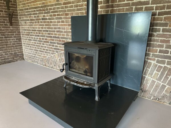 Zwarte houtkachel op een metalen plaat tegen een muur van rode bakstenen binnen in Fortweg.