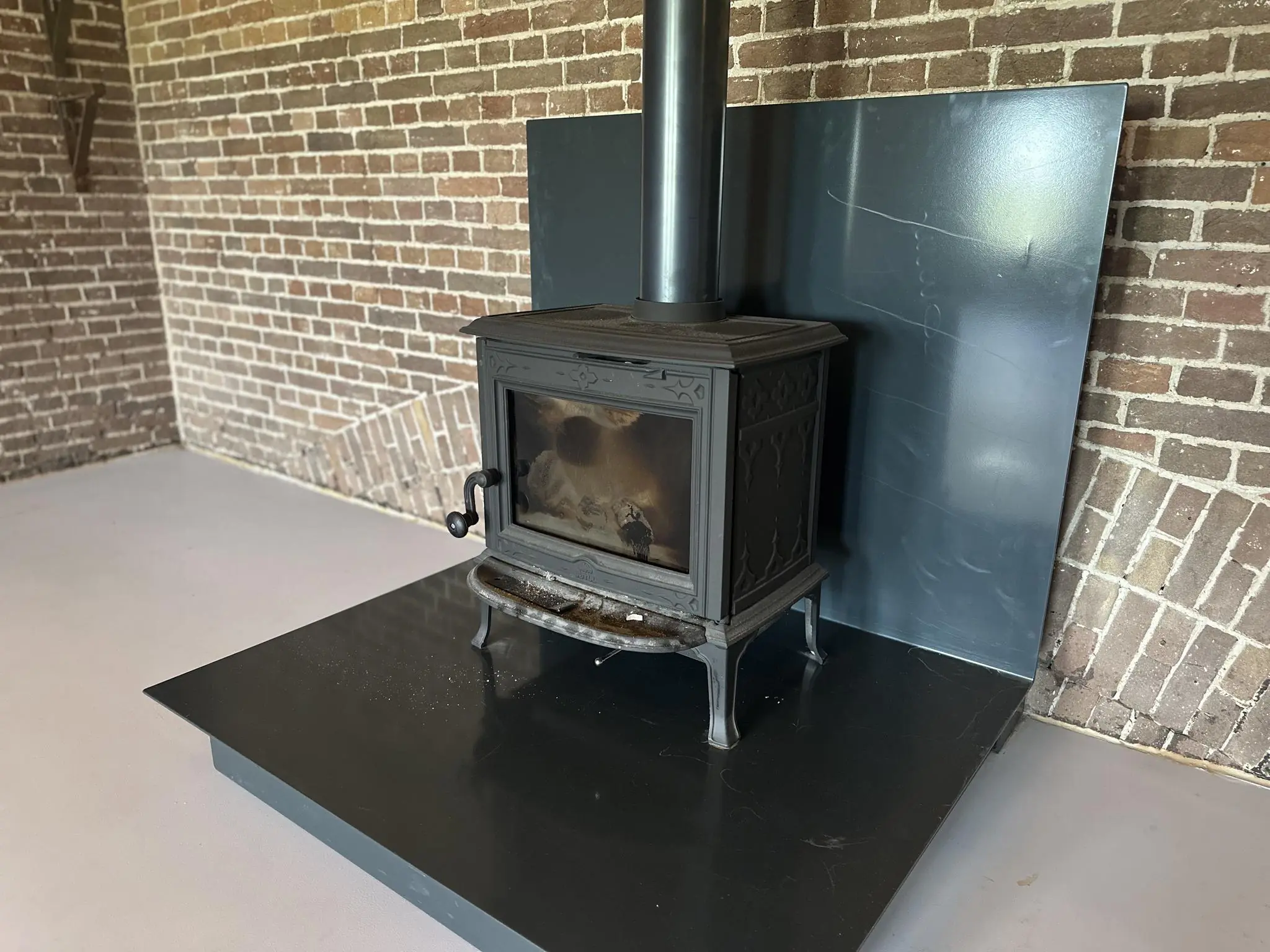Zwarte houtkachel op een metalen plaat tegen een muur van rode bakstenen binnen in Fortweg.