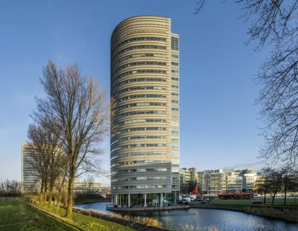 Rond kantoorgebouw 157_2160 aan het water met omliggende moderne architectuur en bomen.