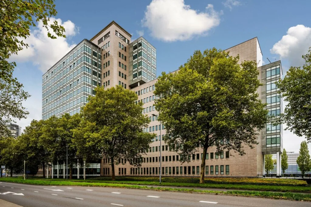 Kantoorgebouw aan de Watermanweg in Rotterdam, omgeven door bomen en gelegen langs een brede weg.