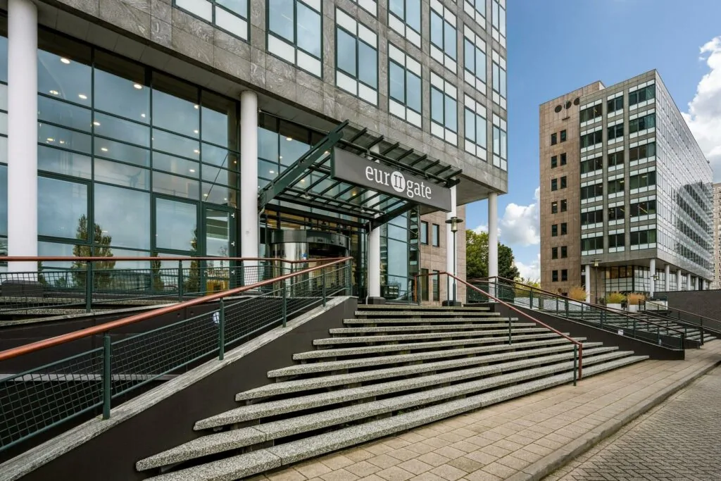 Ingang van het kantoorgebouw "Eurogate" aan de Watermanweg met brede trap en moderne gevel.