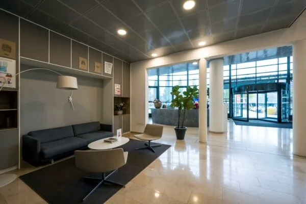 Moderne wachtruimte in de entreehal van een kantoorpand aan de Watermanweg met zithoek en glazen draaideur.