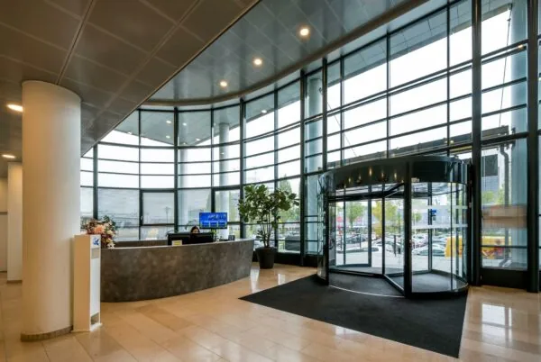 Moderne entreehal met een receptiebalie, glazen draaideur en hoge raampartijen aan de Watermanweg.